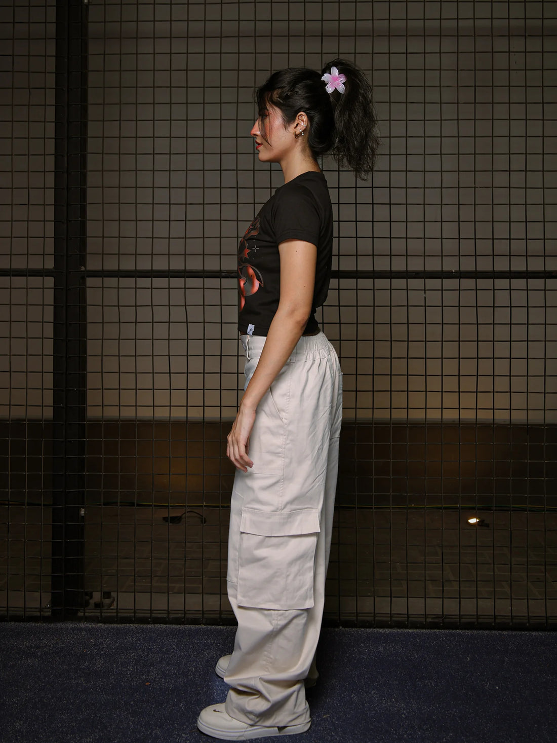 Person wearing a black t-shirt and beige cargo pants standing against a tiled wall.