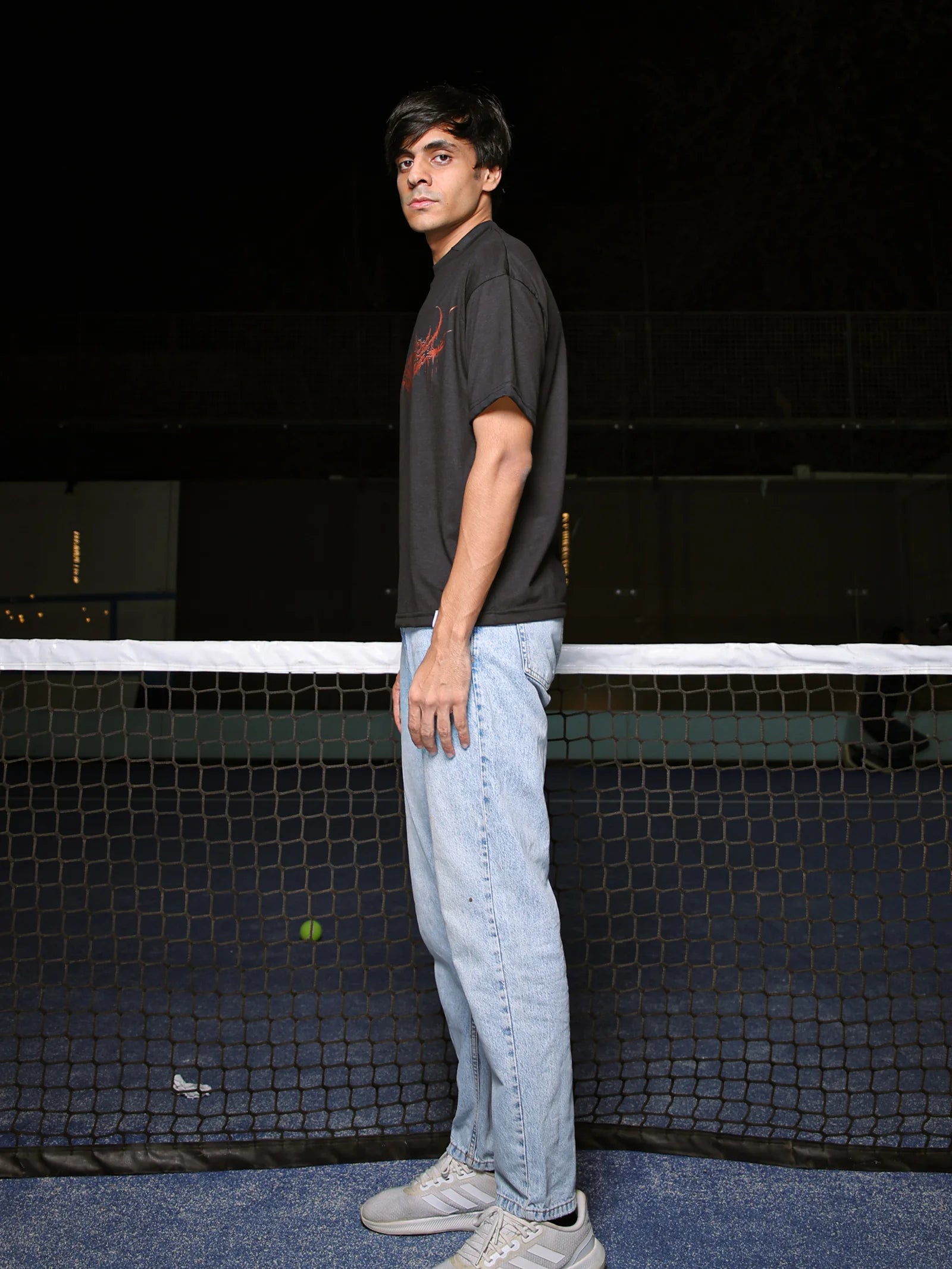 Person standing on a tennis court with a black background
