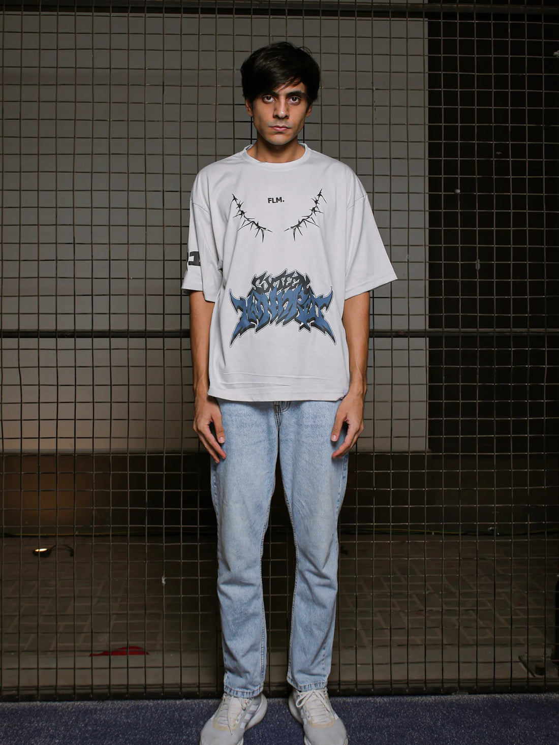 Person wearing a white t-shirt with graphic design in a tiled room