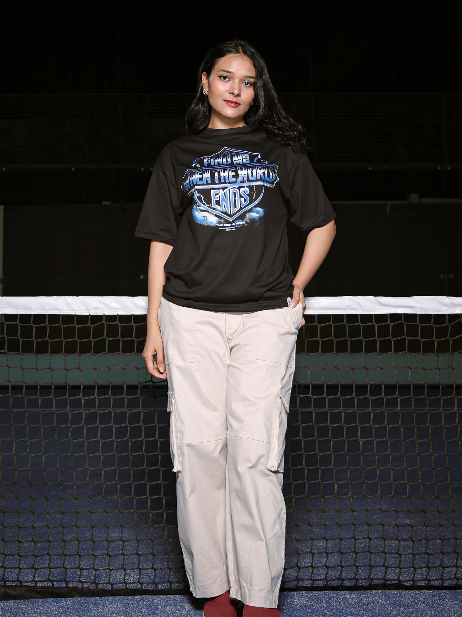 Person wearing a black t-shirt with a graphic design on a tennis court