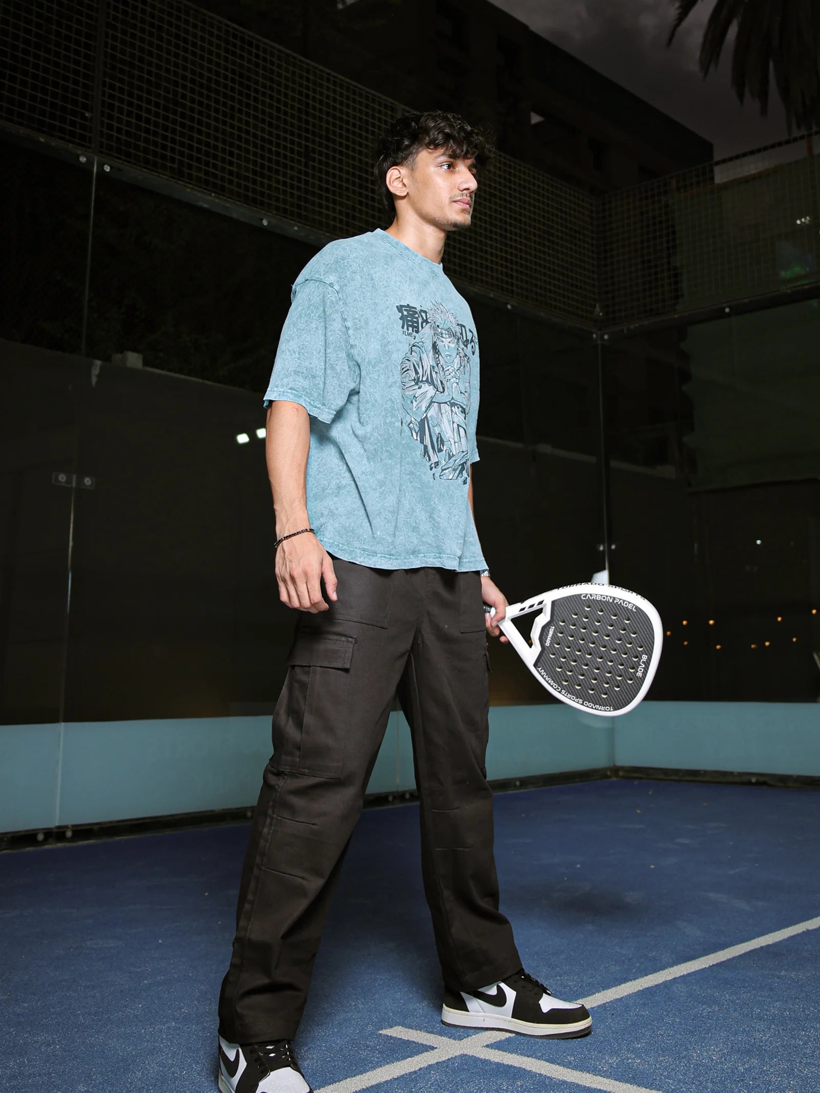 Person holding a paddle on a tennis court at night