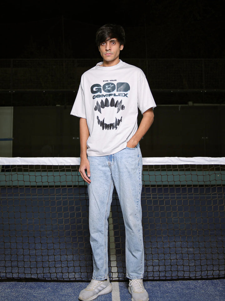 Person wearing a white t-shirt with graphic design and light blue jeans standing on a tennis court.
