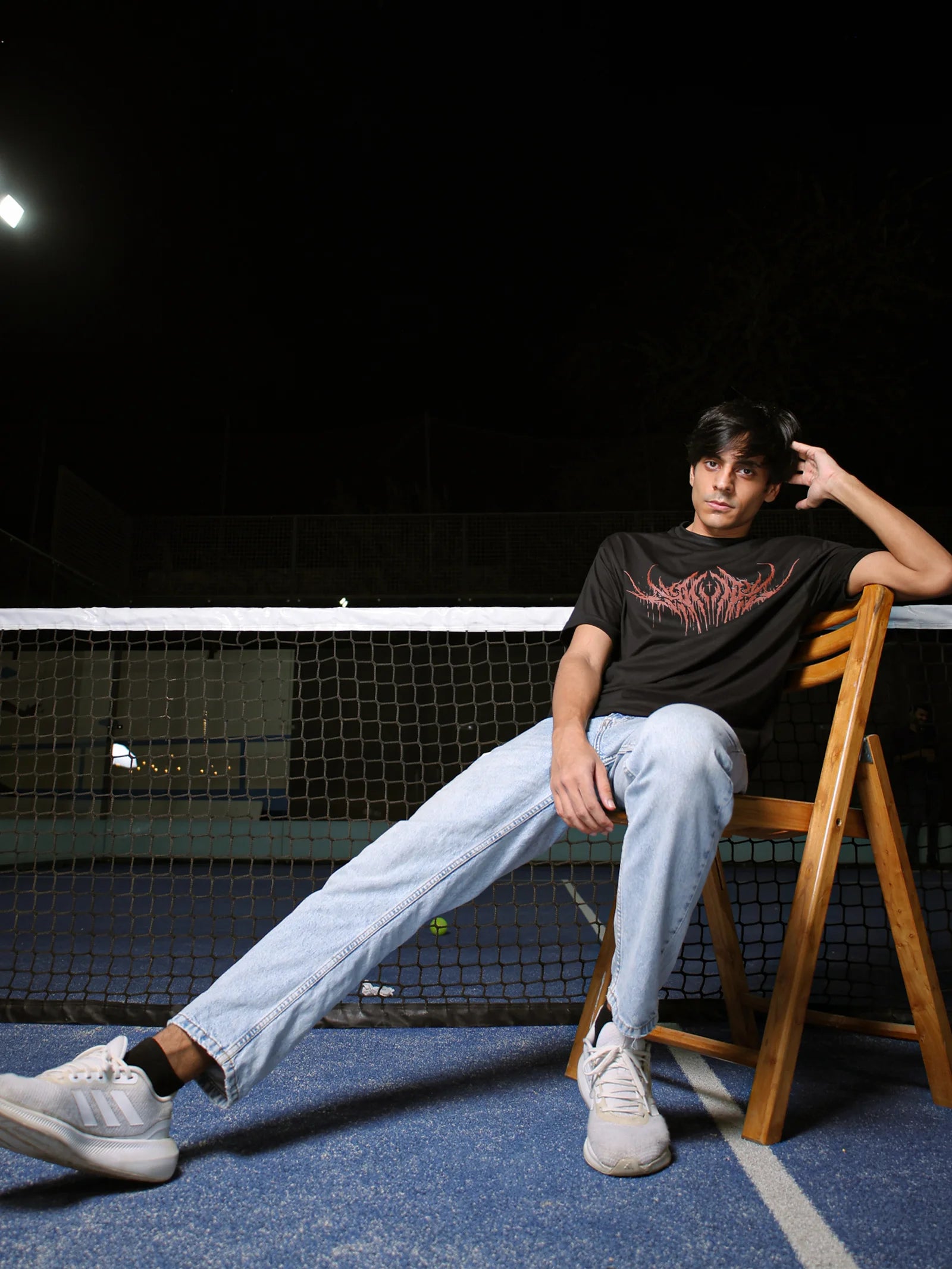 Person sitting on a chair on a tennis court at night
