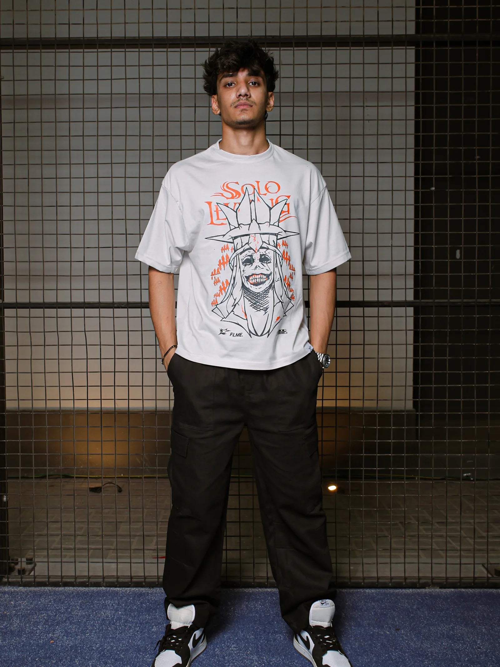 Person wearing a graphic t-shirt with a design on a tiled wall background