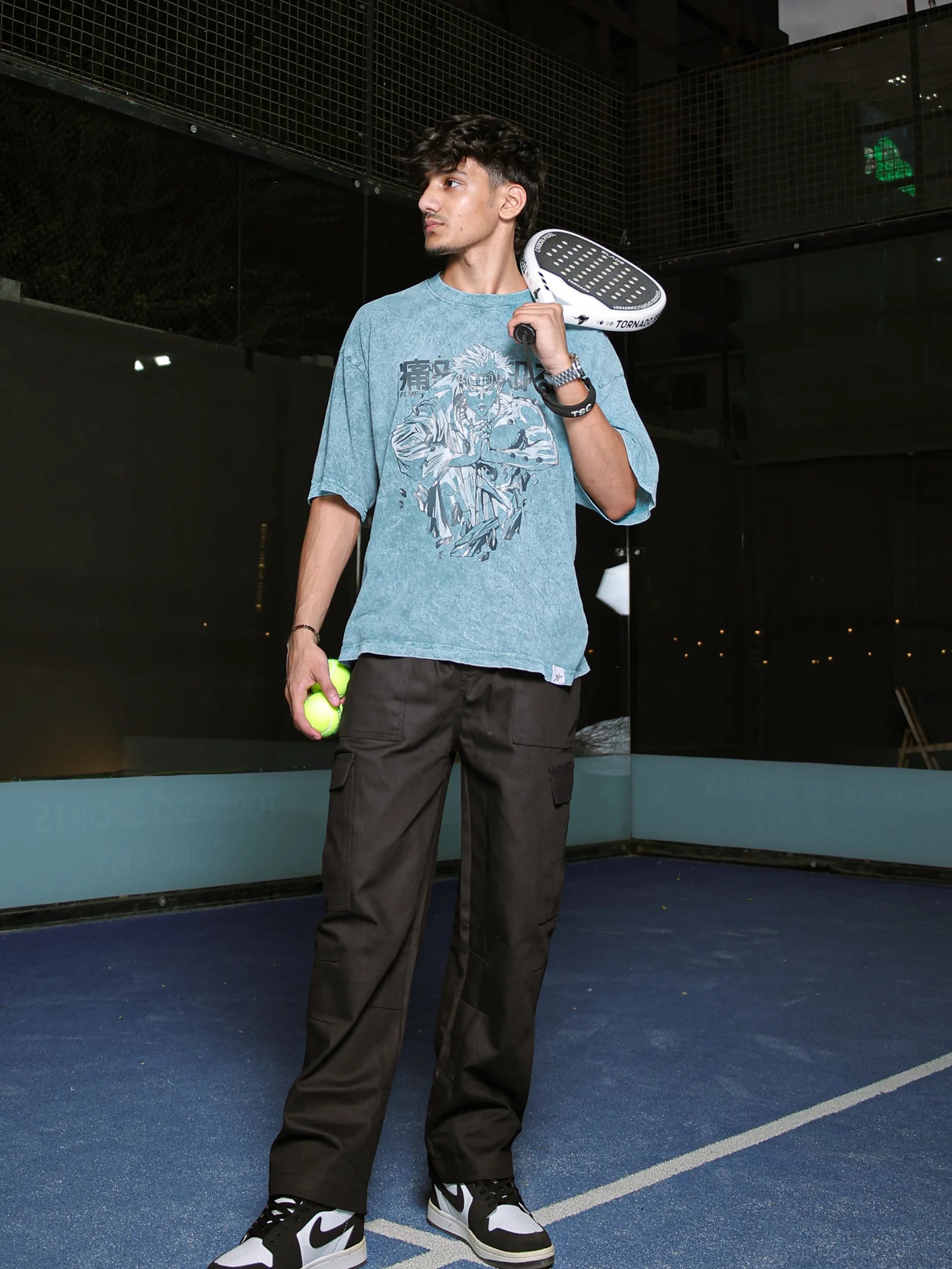 Person holding a sneaker and a tennis ball on a tennis court