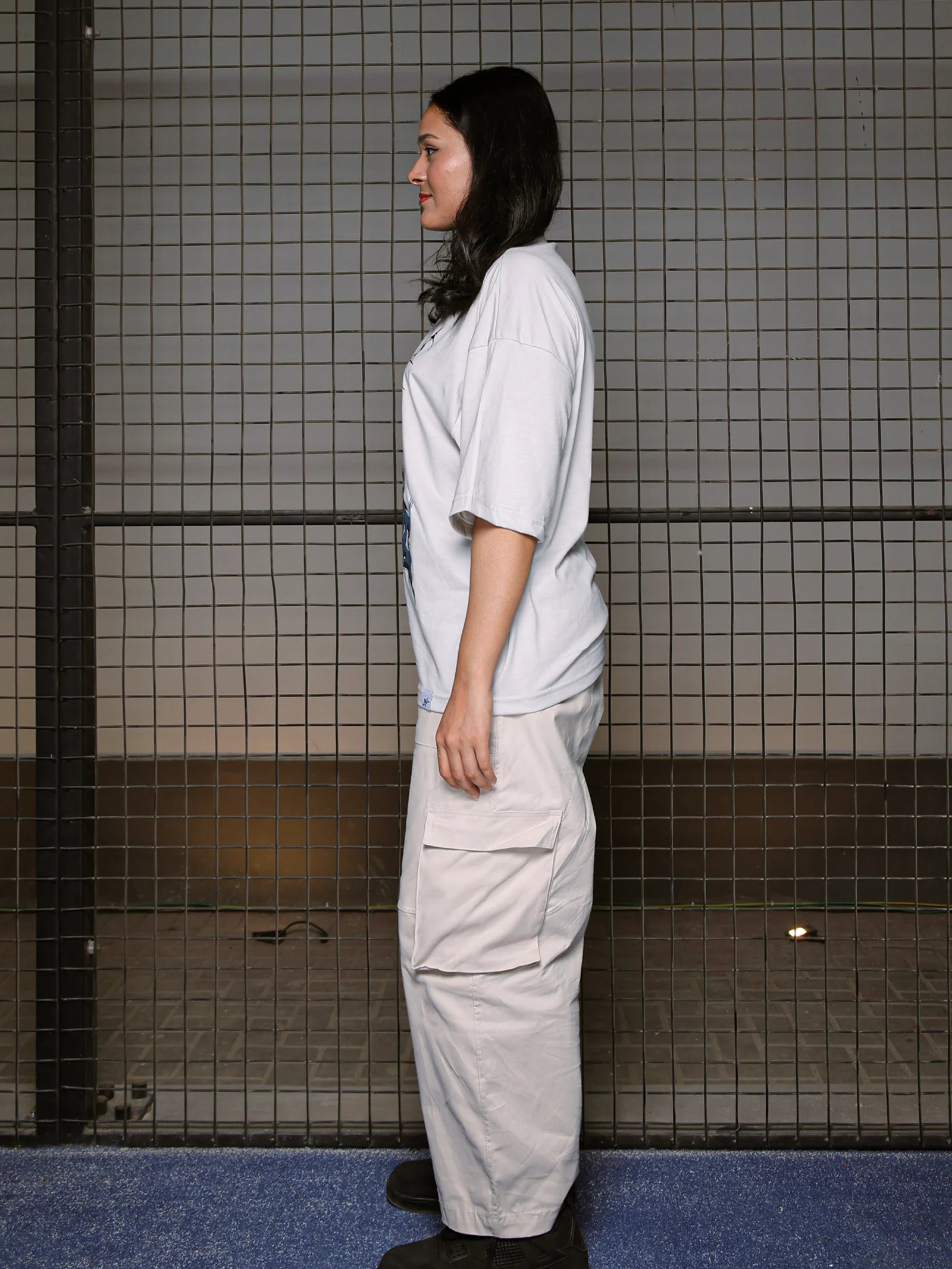 Person wearing a white shirt and light-colored pants standing in a tiled room.