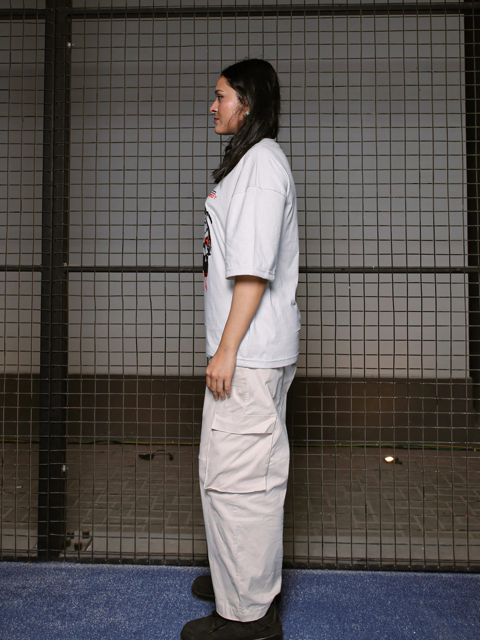 Person wearing a white outfit standing against a tiled wall.