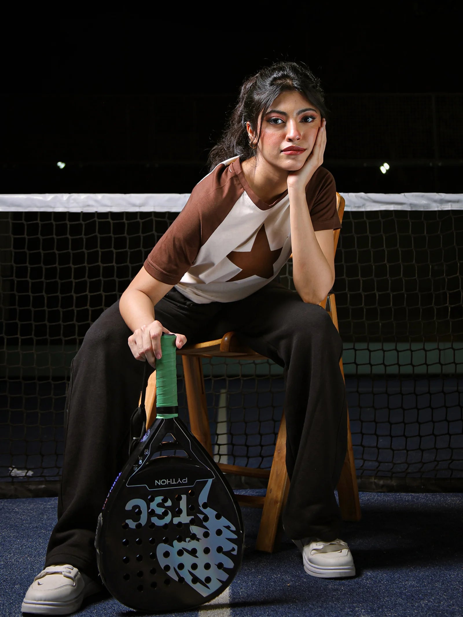 Woman sitting on a chair holding a paddle with a dark background