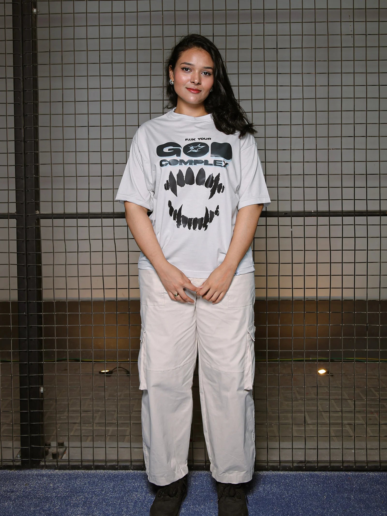 Person wearing a white t-shirt with graphic design and light-colored pants in a tiled room.