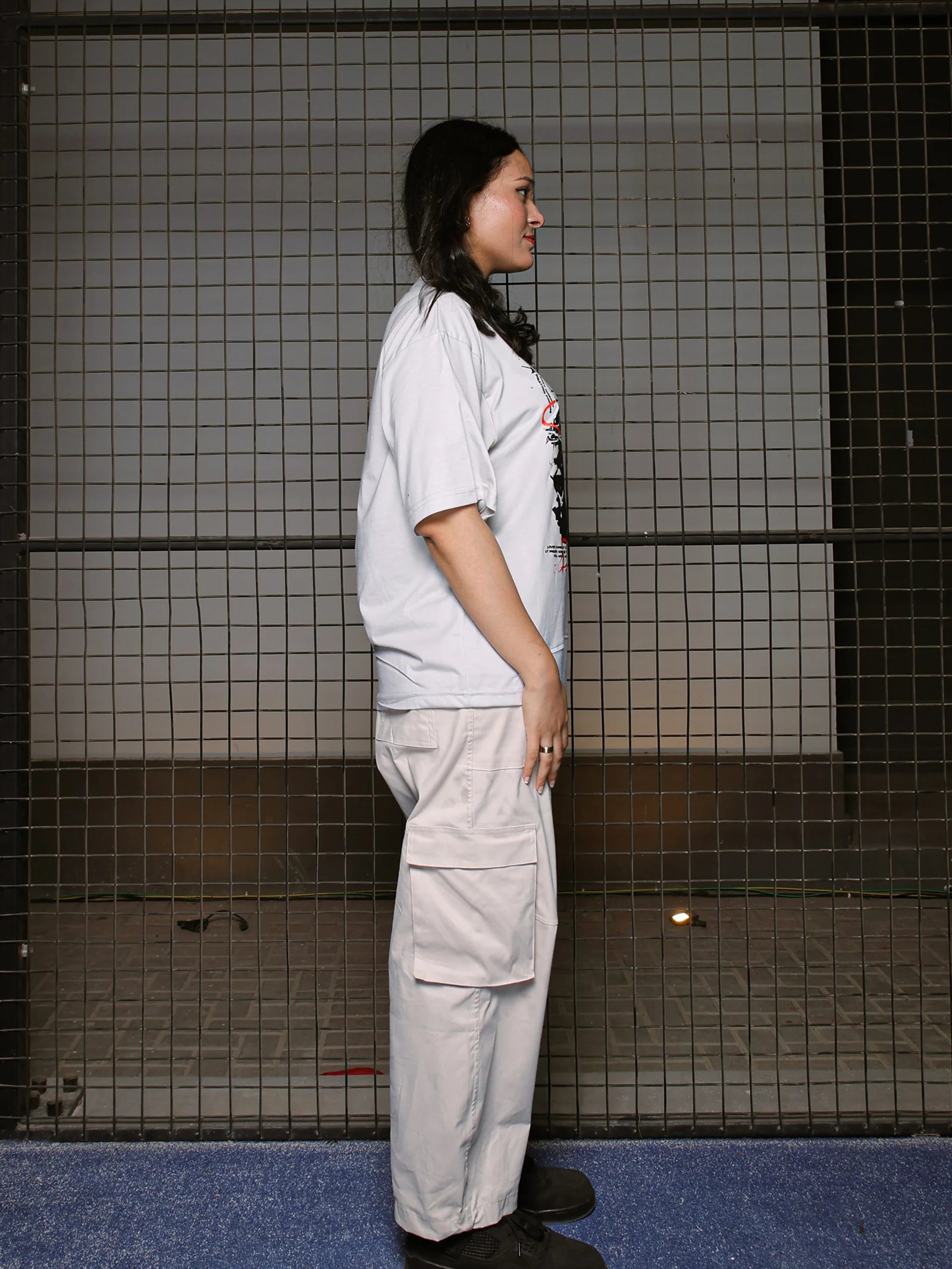Person wearing a white shirt and beige pants standing in a tiled room.