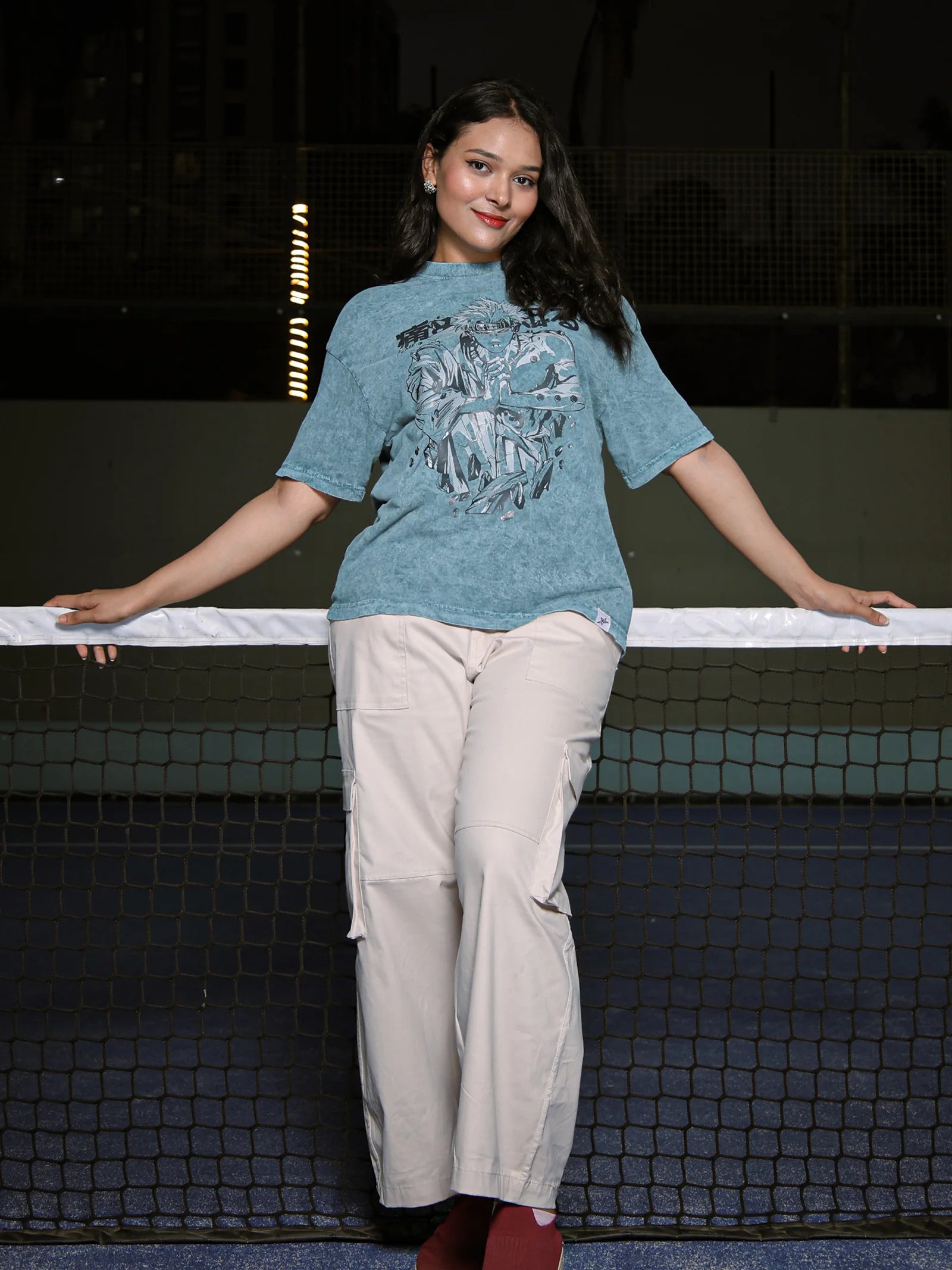 Woman in a blue t-shirt and beige pants standing on a tennis court.
